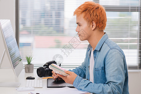 在现代办公室办公桌工作的摄影师工作室电脑商业男人成人技术笔记本男性桌子相机图片