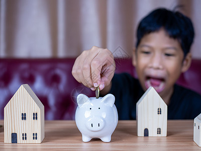 男孩在白猪存钱罐里存钱 储蓄的概念 为未来储蓄微笑童年财富推杆孩子经济男生硬币喜悦幸福图片