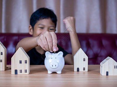 男孩在白猪存钱罐里存钱 储蓄的概念 为未来储蓄硬币童年情感银行钱盒微笑现金货币财富投资图片
