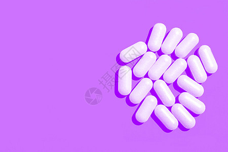 紫色背景上的白色药片胶囊 复制空间图片