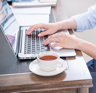 商业概念 穿蓝衬衫的女士在电脑上打字 办公室桌上有咖啡 背光 太阳光亮效应 特写 侧视图 复制空间手机键盘衬衫蓝色逆光工作商务职图片