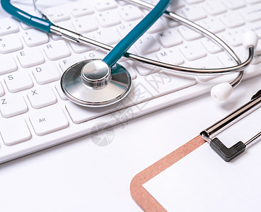 白桌背景的计算机键盘上的蓝色听诊器 在线医疗信息处理技术概念 特写 宏 复制空间GPS办公室框架治疗保健桌子病人笔记医生考试医院图片