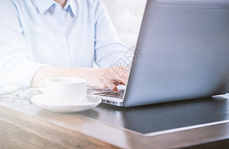 商业概念 穿蓝衬衫的女士在电脑上打字 办公室桌上有咖啡 背光 太阳光亮效应 特写 侧视图 复制空间衬衫自由职业者手机商务电话桌子图片