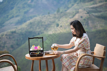 坐在沙椅山风景上 喝着热茶的美丽美女椅子旅行女士假期文化山脉岩石休息餐厅绿茶图片