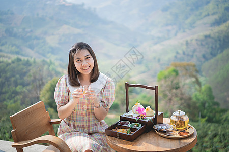 坐在沙椅山风景上 喝着热茶的美丽美女放松杯子桌子假期天空帐篷椅子文化游客女孩图片