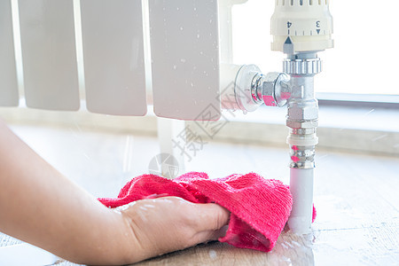 女性手用抹布清洗取暖散热器漏水的水加热湿度设施发热保险洪水管道水分垫圈阀门图片