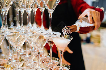 拿着一瓶香槟的人服务美味酒精水晶玻璃金字塔与香槟 浪漫的庆祝活动和党的概念图片