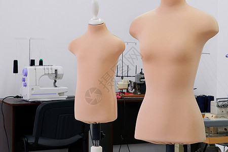 在一家缝纫店的曼金假人 配有背景上的缝纫机 现代美食室工作室白色女性服装纺织品卷尺机器磁带工厂躯干身体图片