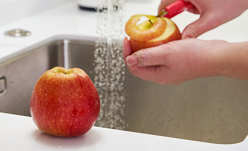 在厨房的洗碗池上方剥苹果的妇女果汁烹饪饮食营养剥皮农业水果女士厨师素食主义者图片