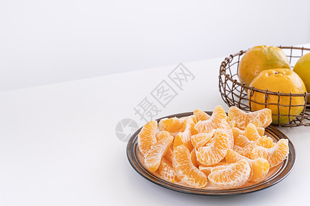 盘子里漂亮的去皮橘子和金属篮子 在现代现代厨房岛的明亮白色干净桌子上隔开摄影热带水果果汁月球服务食物橙子图片