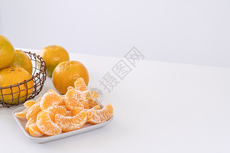 盘子里漂亮的去皮橘子和金属篮子 在现代现代厨房岛的明亮白色干净桌子上隔开食物热带服务橙子月球摄影水果果汁图片