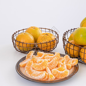 盘子里漂亮的去皮橘子和金属篮子 在现代现代厨房岛的明亮白色干净桌子上隔开服务摄影橙子月球水果热带果汁食物图片