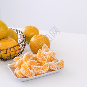 盘子里漂亮的去皮橘子和金属篮子 在现代现代厨房岛的明亮白色干净桌子上隔开果汁食物橙子摄影月球热带水果服务图片