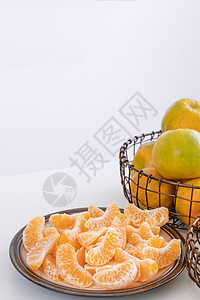 盘子里漂亮的去皮橘子和金属篮子 在现代现代厨房岛的明亮白色干净桌子上隔开果汁食物摄影服务热带水果月球橙子图片