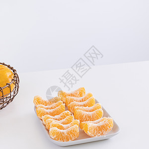 盘子里漂亮的去皮橘子和金属篮子 在现代现代厨房岛的明亮白色干净桌子上隔开热带橙子食物摄影果汁水果月球服务图片