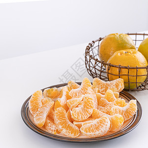 盘子里漂亮的去皮橘子和金属篮子 在现代现代厨房岛的明亮白色干净桌子上隔开月球摄影水果热带果汁橙子食物图片