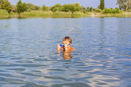 在炎热的夏日 一个快乐的孩子正在河里游泳 在水库游泳 一个幸福的家庭在夏天玩得开心 在水中嬉戏闲暇热带池塘泳装海洋水池乐趣孩子们图片