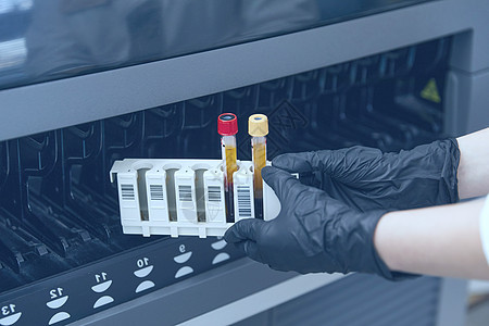 女科学家将血液样本测试管放入分析器医疗机器中 在实验室使用现代医疗设备进行科学工作;蓝色提宁 (blu Ting)图片