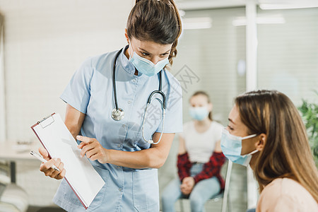 在等候室与护士交谈的有保护面罩的妇女焦点女性诊所门厅疾病病人医生水平防护面具图片