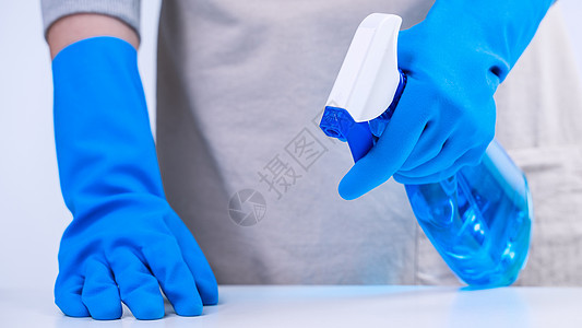 年轻女管家正在用蓝手套 喷雾清洁剂 湿黄色抹布 闭合 复制空间 空白设计概念在围裙内打扫白桌蓝色除尘器女士服务清洁度工人桌子毛巾图片