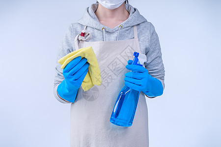 穿围裙的年轻女管家正在用蓝手套 湿黄抹布 喷洒瓶装清洁剂 特写 复制空间 空白设计概念来打扫清洁工工作家政瓶子家务洗涤剂家庭女孩图片