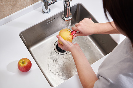在厨房的洗碗池上方剥苹果的妇女女士素食主义者营养果汁饮食剥皮农业水果女性厨师图片