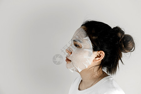 身穿白T恤的亚洲妇女侧面观 并用面具遮盖脸部治疗床单温泉化妆师女孩柔软度滋润清洁卫生美容图片