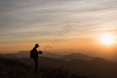 与多彩的暮光天空对着悬崖拍摄摄影师Silhouettes拍照照片太阳相机三脚架橙子游客爱好女性假期图片