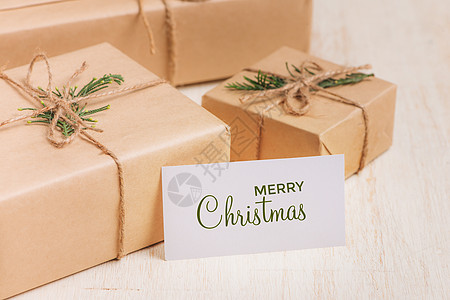 圣诞或新年礼品盒收藏 包装在木质背景的Kraft纸上桌子空白卡片盒子展示丝带白色礼物标签假期图片