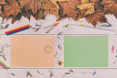 空的彩色纸和木桌上的学校用品及秋叶假图片