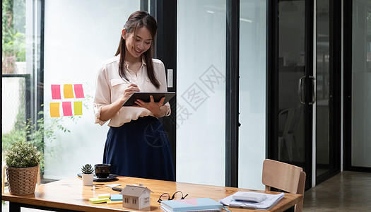 拥有平板牌和站在现代办公室的快乐女经理 亚洲女性使用石板 商业财务会计概念的图卢斯(Stulus)图片