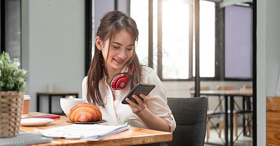 玩音乐的女孩使用智能手机在线会议视频电话时戴耳机的亚裔女性屏幕微笑青少年技术电脑商业女士展示工作细胞背景