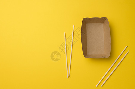 黄色背景 顶视图上方的空棕色纸板和木筷子 可使用餐具食物工具浪费寿司美食竹子传统木头用具厨房图片