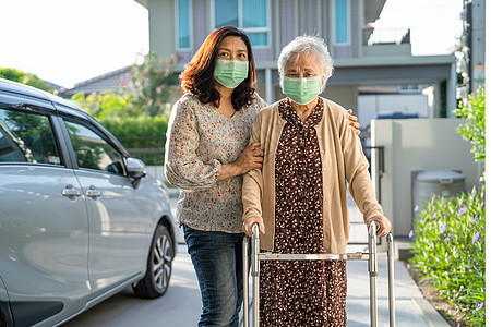 亚洲年长或老年老年妇女带着行尸走路 并戴面罩以保护安全感染Covid19 Corona病毒的安全行车椅子医院机动性花园甘蔗房子保图片