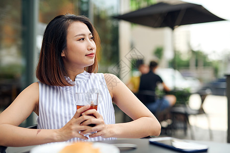 清晨坐在户外喝咖啡的美丽的女人羊角杯子早餐食物微笑女士女孩电话女性咖啡店图片