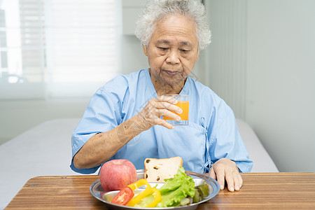亚洲年长或年长的老妇人病人在医院的床上坐着饿着肚子 满怀希望和快乐地吃着早餐蔬菜健康食品裁剪女士医生说谎手术办公室男人孩子保健诊图片