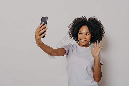 快乐的年轻女性一边用现代智能手机与最好的朋友进行视频通话 一边对着镜头挥手图片