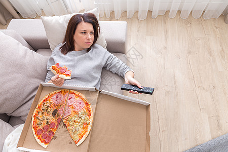 女人吃披萨的画面 从上面拍摄盒子桌子阅读手表房间小吃沙发食物女性孤独图片