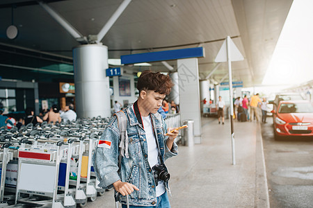 在机场等待出租车时 微笑的人发短信的肖像互联网电话城市技术车站游客人士手机旅行飞机场图片