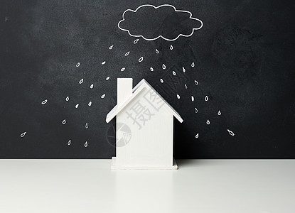 木屋和用白色粉笔在黑色粉笔板上绘制的云雨 房地产保险概念图片