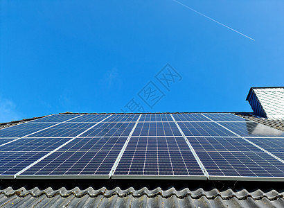 屋顶太阳能太阳能电池板在有黑色屋顶砖的住宅房顶顶上生产清洁能源商业生态回收创新太阳能太阳集电极力量蓝色光伏背景