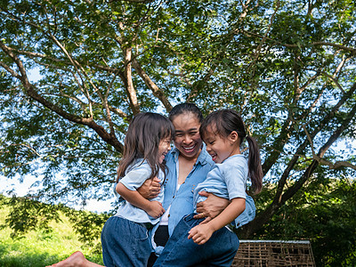 两个兄弟姐妹的小女孩和妈妈在温暖而阳光明媚的夏日在花园里互相欢笑和拥抱 年轻的女孩和她的母亲在公园里度过一天娱乐晴天幸福情感父母图片