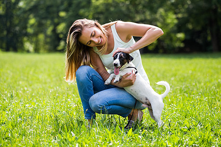 女人和她的狗杰克罗素泰瑞 在大自然中度过时间公园乐趣小狗阳光哺乳动物女性喜悦动物忠诚微笑图片