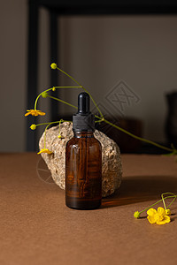 棕色玻璃瓶化妆品或油在石头和米色棕色纸背景上的黄色野花 具有硬阴影的美容概念护理身体品牌碳粉博客温泉药品标签静物推广图片