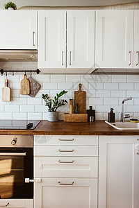厨房黄铜器具 厨师配件 有白色瓦片墙壁和木桌面的垂悬的厨房 厨房背景的绿色植物家具装饰内阁桌子住宅器具风格台面木板瓷砖图片