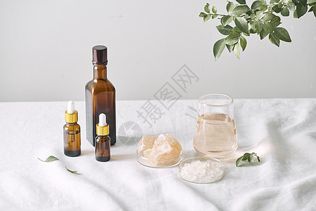 芳香疗法 装有化妆品油的小玻璃瓶 浴盐 新鲜的叶子 用于白色背景油 叶的 spa 程序的对象手工温泉椰子奶油身体洗澡配件皮肤按摩图片