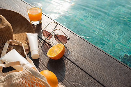 三维游泳池游泳池附近的海滩帽 橙汁和太阳眼镜洗剂奶油橙子防晒霜紫外线太阳化妆品假期皮肤身体背景