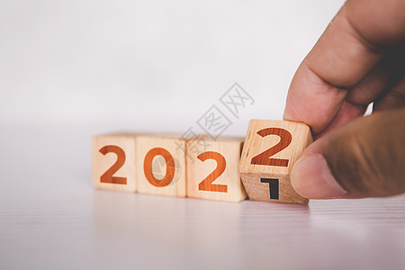 双手翻转立方体木块 文字为 2022 年 开始和趋势 日历和时间 确定目标和成就规划 动机和愿望 商业概念战略木头行动进步新年数图片