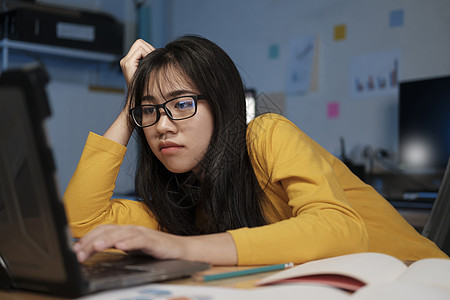 在办公室用笔记本电脑工作的年轻妇女自由职业者工人学习专注技术焦虑风镜女性职场商务图片