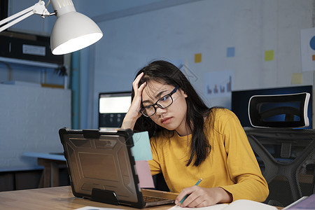 在办公室用笔记本电脑工作的年轻妇女过夜自由职业者女性学生员工工人学习职场商业技术图片